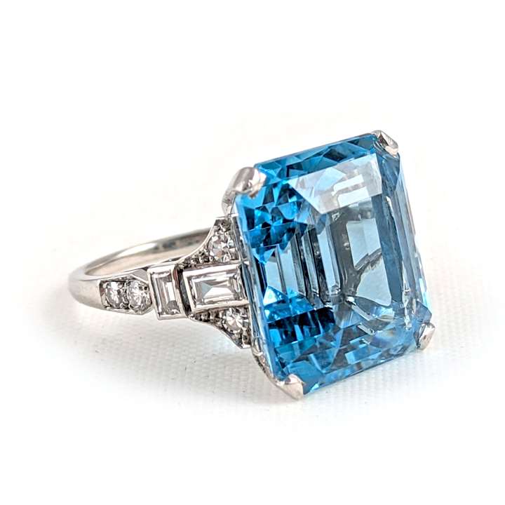 Art Deco aquamarine and diamond dress ring, c.1935, claw set with a cut-corner rectangular aquamarine of step cut, approximately 14.20ct,